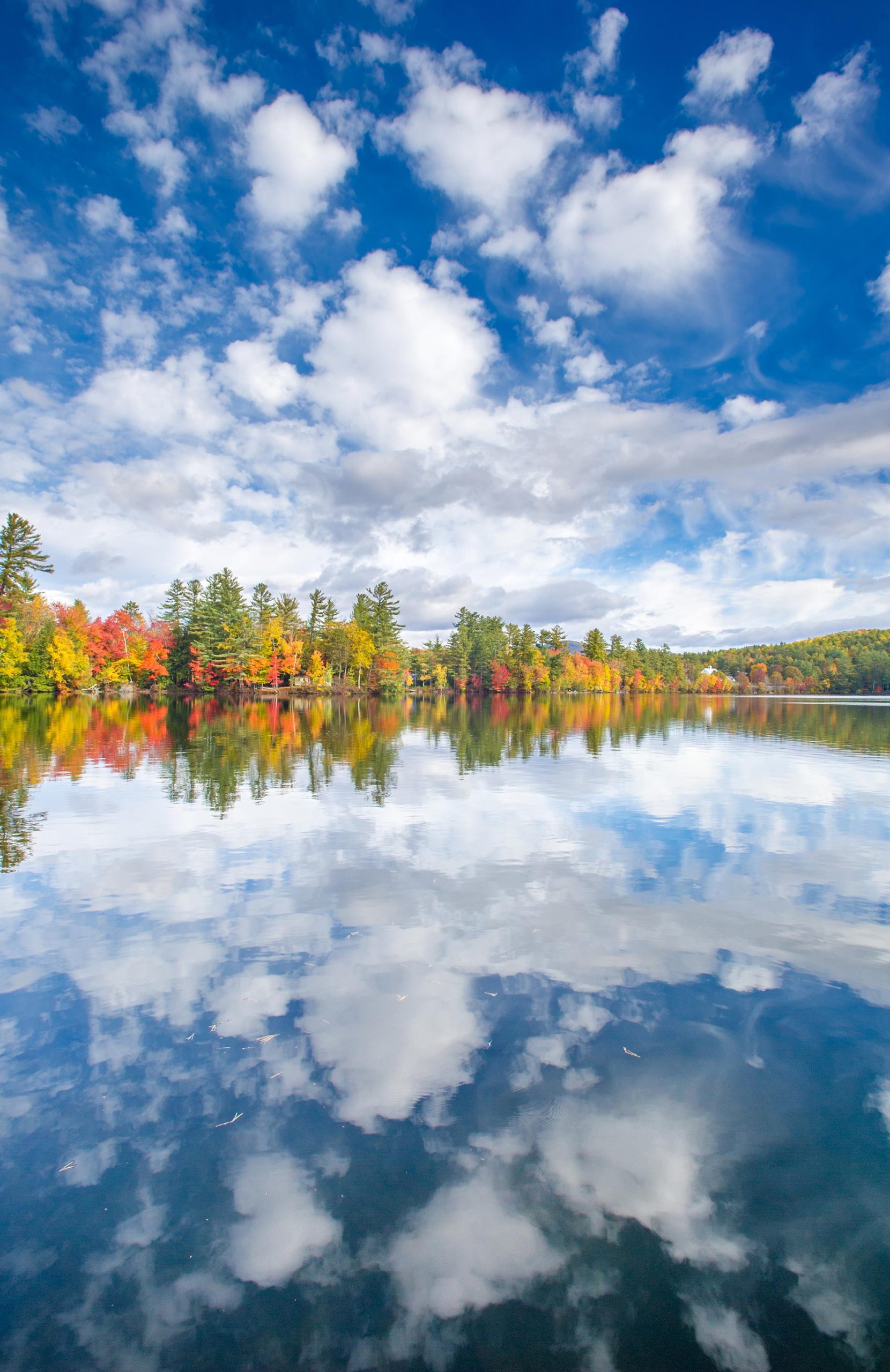 a sky filled with clouds and the reflection of the clouds in Bryant Pond - Autumn colored leaves on the trees