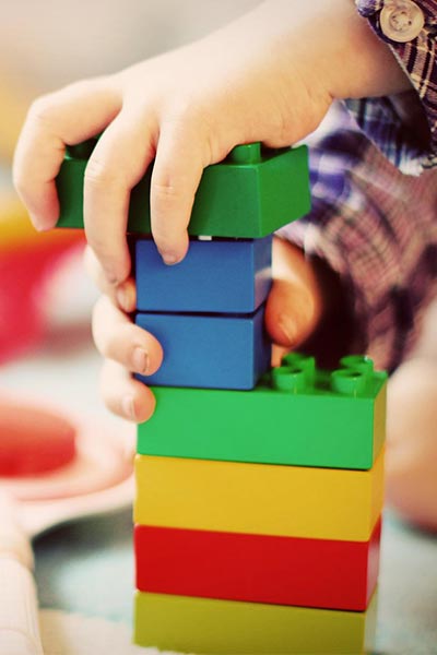 a child's hands working with building blocks to build a structure