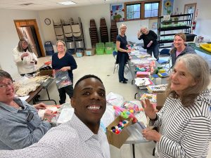 a group of adults who are board members prepping materials for youth group crafts and educational games