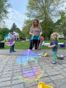 two adults playing with bubble wands with a toddler