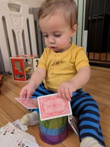 young child trying to put cards in a can