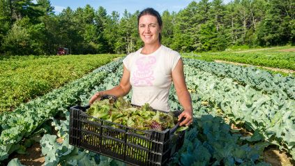 woman farmer with lettuce standing in field
