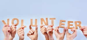 several hands holding up letter that spell volunteer