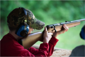 Boy holding rifle with hat and ear protection