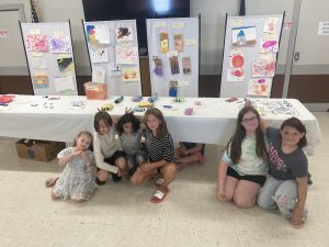 6 youth in front of a table. The youths artwork is on the table