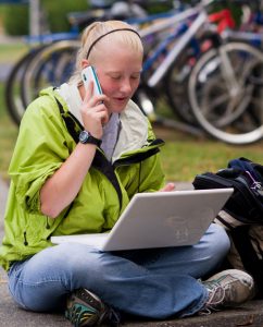 student talking on cellphone while using laptop