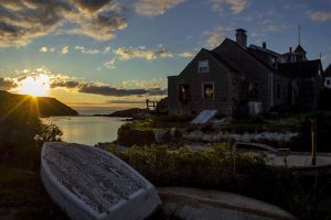 a few of a overturned row boat and house on Monhegan Island, Maine at sunset