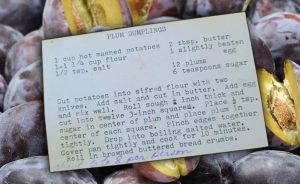 Plum Dumplings recipe card overset on an image of prune plumbs background