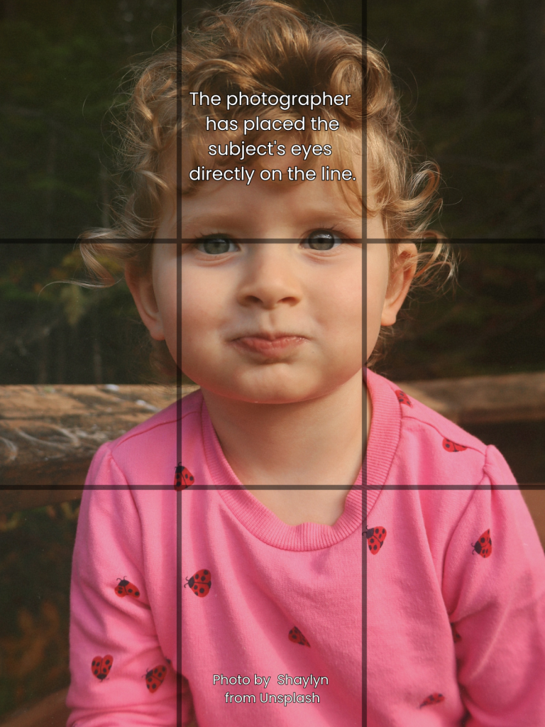 A photo of a child with a grid overlay showing that the photographer has placed the subject's eyes directly on the top line.