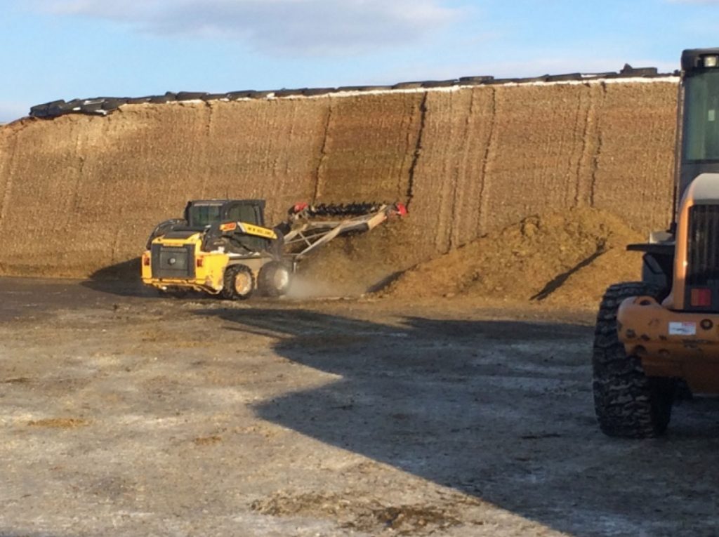 Facer in action “raking” the face of a bunker of corn silage.