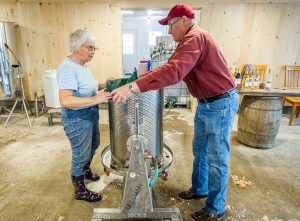 Two older farmers pressing apple cider