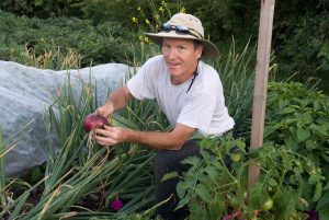 Extension expert harvests produce from a local community garden; photo by Edwin Remsberg.