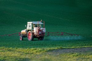 Farm tractor spraying pesticides on a cover crop