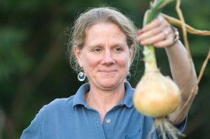 gardener proudly holds up a large onion