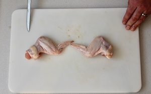 Photo of raw chicken showing wings cut from whole chicken.