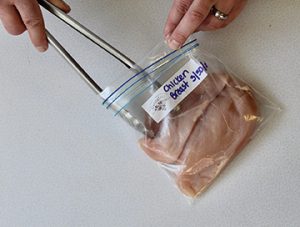 Photo showing inserting chicken pieces into a freezer resealable bag for storing.