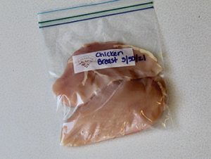 Photo showing chicken pieces in a freezer resealable bag for storing.