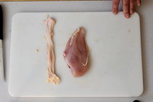 Photo of raw chicken and how to remove the skin from the drumstick, hold the drumstick at the end with the most meat and pull the skin toward the opposite end with your other hand.