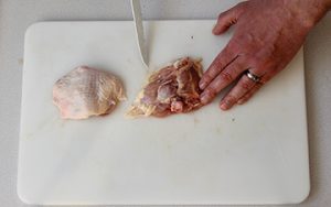 Photo of raw chicken showing removal of the bone from the thigh.