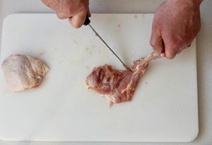 Photo of raw chicken showing removal of the bone from the thigh.