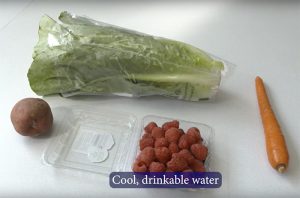 Cutting board with lettuce, potato, rasberries and carrot. Wash fruits and vegetables with cool, drinkable water.