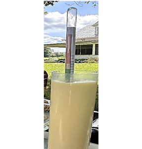 A close-up view of a colostrometer in a cylinder full of colostrum