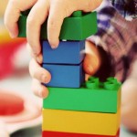 a-childs-hands-working-with-building-blocks-to-build-a-structure
