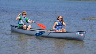 2 campers paddle a canoe