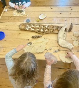Play-based learning in action! Participants use natural objects to make imprints in homemade play dough