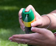 Woman sprays insect repellent into her hand