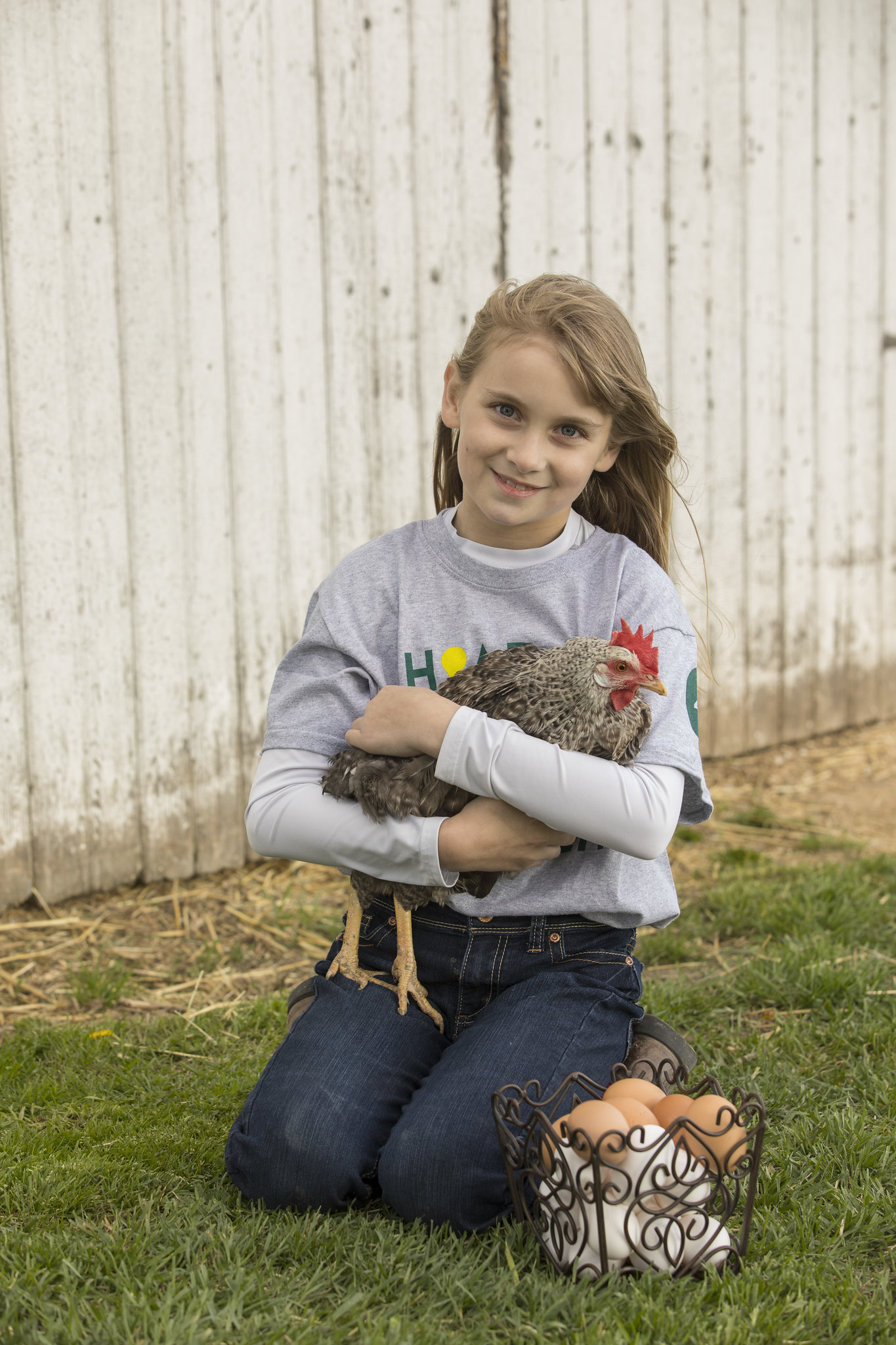 4-H member holding a chicken next to a basket of eggs