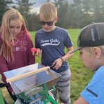 three youth participate in apple cider pressing