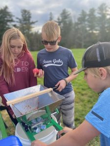 three youth participate in apple cider pressing