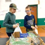 two youth fill bags of goodies