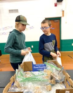 two youth fill bags of goodies