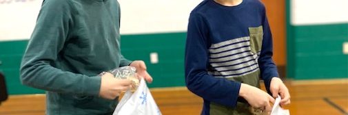 two youth fill bags of goodies