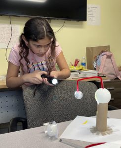 Youth learns about the eclipse by making a model.