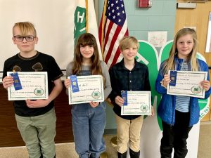 Four 4-H youth display their certificates and ribbons.