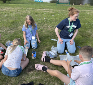 staff with 4-H'ers outside sitting in grass during a program