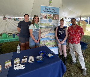 staff standing by a sign at the fair