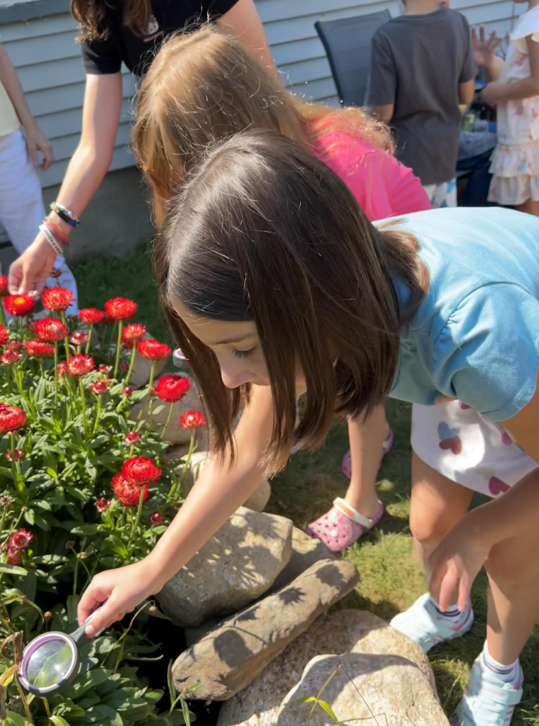 Youth inspect plants and bugs with a magnifying glass. 