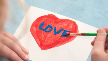 4-H'er paints a heart and the word "love" on a card