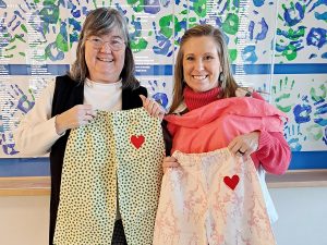 Extension Homemakers State Director Lisa Fishman delivers pajamas to Nicole Cooley, Development Director of the Boys and Girls Clubs of Kennebec County.