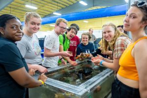 4-H students exploring an aquatic touch tank while touring the Center for Cooperative Aquaculture Research (CCAR) facility