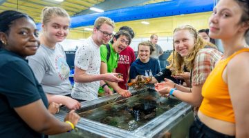 4-H students exploring an aquatic touch tank while touring the Center for Cooperative Aquaculture Research (CCAR) facility