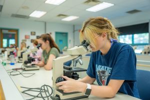 Student looks at phytoplankton under a microscope