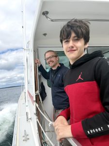 Teen posing next to an adult on a boat.