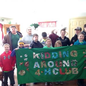 Kidding Around 4-H Club members pose with a banner